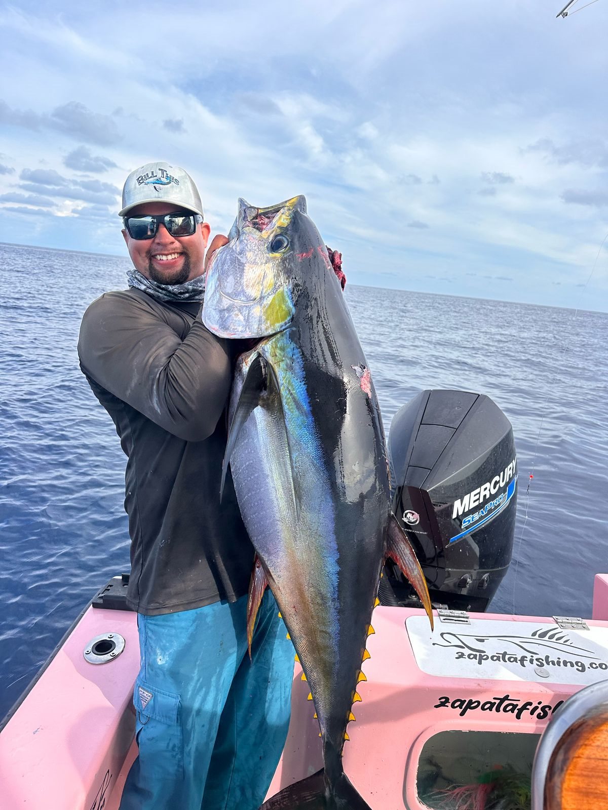 Adult angler smiling beside an exceptionally large yellowfin tuna