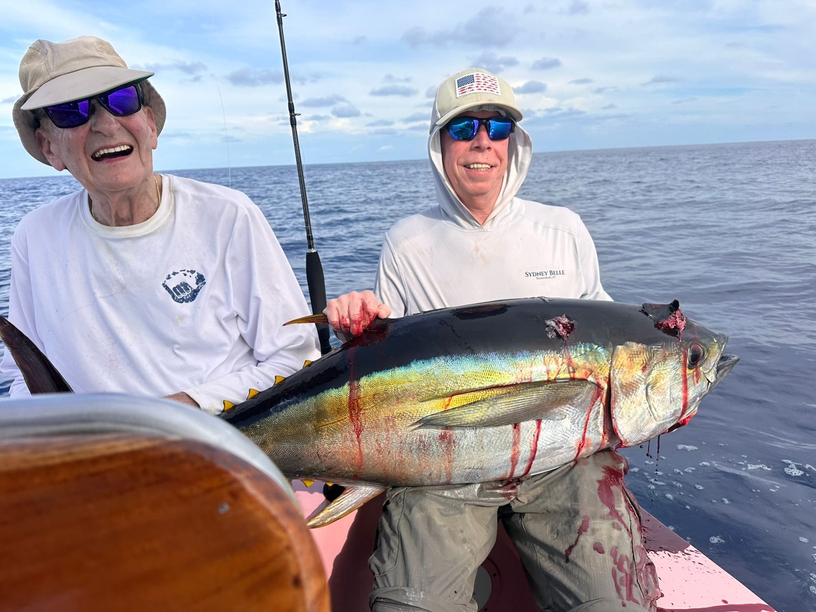 Two anglers smiling behind a yellowfin tuna