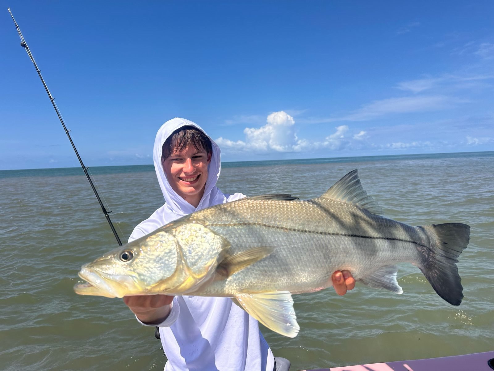 Young adult angler smiling with a large snook