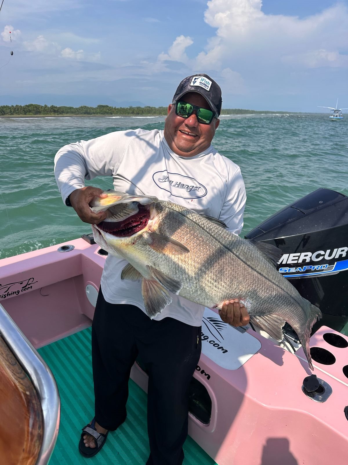 Captain Roy Zapata holding a large snook aboard the pink Zapata Fishing boat